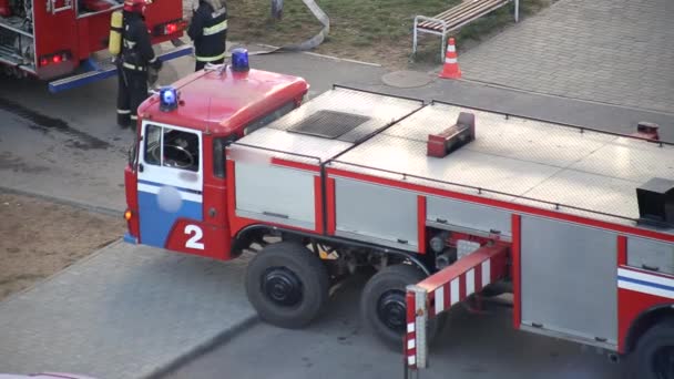 Flygplattform brandbil med blinkande ljus mitt bland en skara brandmän som släcker en brand. — Stockvideo