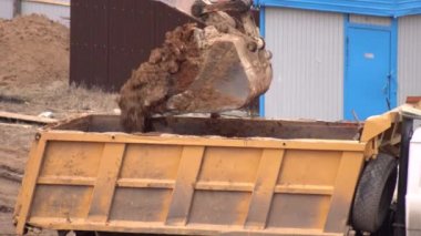 Bir kazıcı, inşaat alanında bir kamyona kum yüklüyor, endüstri. Toprak taşıma, bina inşaatı, arkaplan