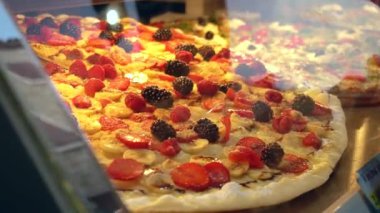Taze ahududu ve böğürtlenli lezzetli tatlı pizza, pencerede muz pizzası satılıyor. Sokak yemekleri, sebzeler.