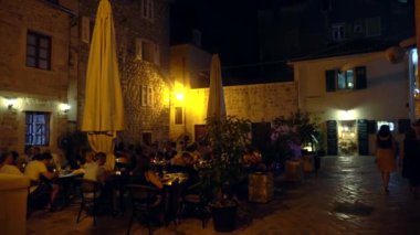 KOTOR, MONTENEGRO - 1 Temmuz 2019: Taş binalar ve kafeler, yürüyen insanlar ve turistler ile eski Kotor kasabasının sokakları