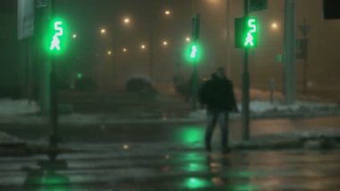 Bulanık, trafik ışıklarına odaklan. Adam gece vakti yaya geçidine doğru koşuyor. Kırmızıya döner ve yeşil yanıp söner. Kışın sis. Islak asfalta yansıyor. Farlardan gelen ışık.