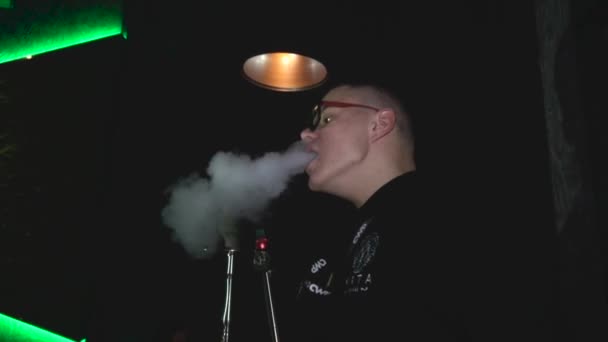 BOBRUISK, BELARUS 02.29.20: hookah man exhales smoke or steam from his mouth and nose in night club — Stock Video