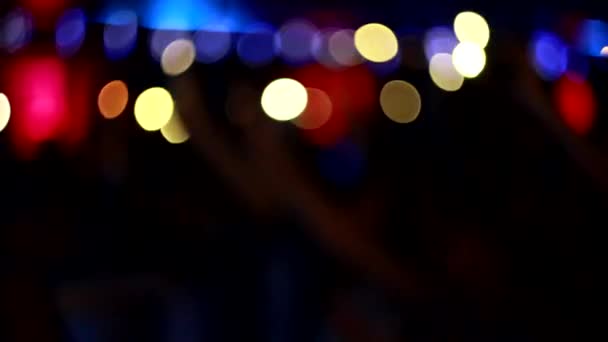Mensen zwaaien met hun armen en houden licht tegen zaklampen in een nachtclub, achtergrond, slow motion, podium voor optreden, wazig — Stockvideo