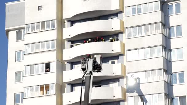 Camión de bomberos plataforma aérea levanta bomberos en una cesta protectora para extinguir un incendio en un edificio de gran altura de varios pisos, bombero — Vídeo de stock