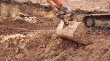 Bir kazıcı temel oluşturmak için bir temel çukurunda kil toprak kazar. Zemin, arka plan, endüstri ile kazıcı demir kovası