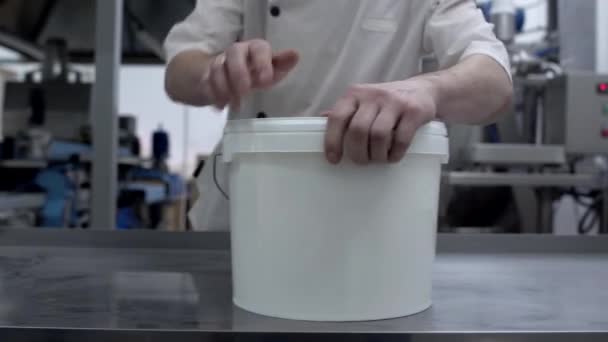 Il lavoratore chiude un secchio di latticini finiti. Il concetto di fare il latte, panna acida e panna, spazio copia — Video Stock