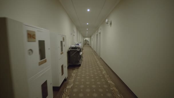 Charwomans cart is in hotel corridor during cleaning of room by cleaning lady. Luxury motel or hostel. Maid, no one and nobody. Wide angle lens steadicam gimbal shot. Housemaid — Stock Video