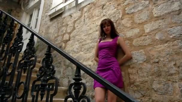 Bella ragazza caucasica posa su una vecchia scala architettonica contro un muro di pietra in città. Vecchia architettura, slow mo — Video Stock
