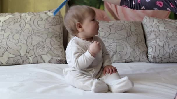 Мать расчесывает расческу маленького мальчика в возрасте 8 месяцев, белый — стоковое видео