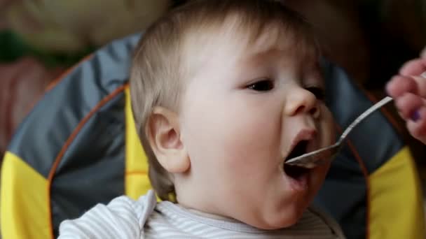 작고 잘생긴 남자 애가 숟가락으로 죽을 먹을 거야, 클로즈업해서. 약 한 살된 어린이의 영양 섭취, 배경, 코카서스 — 비디오