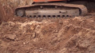 Sürüngen kazıcı bir inşaat sahasında kovayla toprağı kazıyor, yakın plan, endüstri.