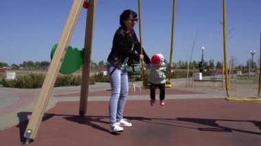 Küçük güzel beyaz kız annesiyle oyun parkında oynuyor. Güneşli bahar havası arka plan, açık hava