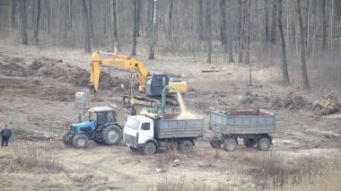 Özel bir odun öğütücüsü olan bir traktör ağaçları odun parçalarına ayırıyor. Kamyon gövdesine, sanayiye, makineye odun parçaları yüklüyorum.