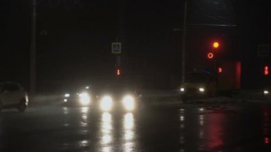BOBRUISK, BELARUS - 01.12.20: arabalar, araçlar kavşakta ilerliyor. Kışın sisli bir gece şehri. Islak asfalta yansıyor. Farlardan gelen ışık.