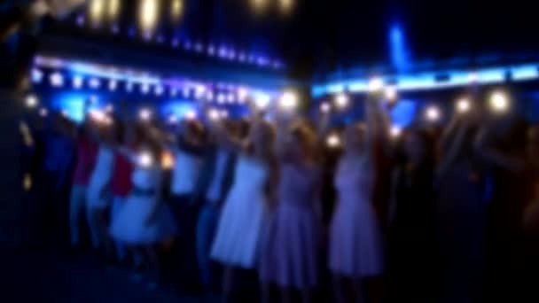 Люди махають руками і тримають світло від ліхтарів у нічному клубі, фоні, повільному русі, сцені для виконання, розмитому — стокове відео