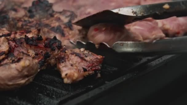 Kucharz przygotowuje świeże mięso na grillu, odwraca mięso do jednolitego smażenia. Soczysty apetyt Mięso jest grill, slow mo, grillowane mięso — Wideo stockowe