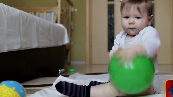 Pequeno menino lindo é jogado com brinquedos em casa. Rapaz de 8 meses, caucasiano. Grandes olhos castanhos — Vídeo de Stock