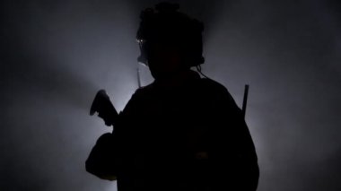 Askeri teçhizatlı asker, siyaha boyanmış ateşli bir silahla. Arka plan, askeri operasyonlar, yavaş çekim