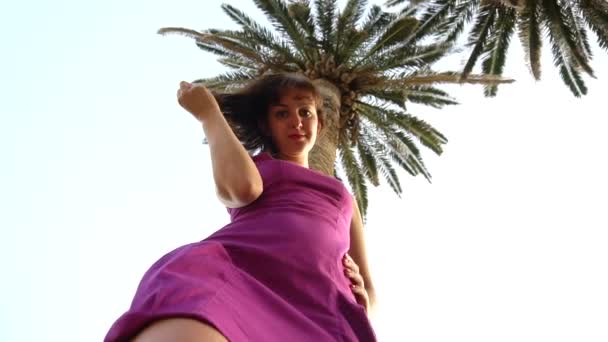 Nice brunette girl looking at the camera on a background of palm trees and blue sky, background, slow motion, caucasian — Stock Video