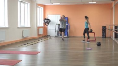 Genç beyaz kız eğitmen sakallı bir adamı spor salonunda yağ yakmak için eğitiyor. Aşırı kilolu Sorunlar, Sağlık