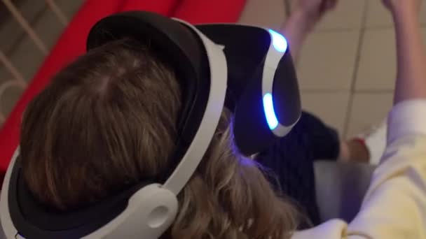 Une jeune fille joue dans une console informatique moderne en utilisant un joystick et des lunettes de réalité virtuelle, la technologie 