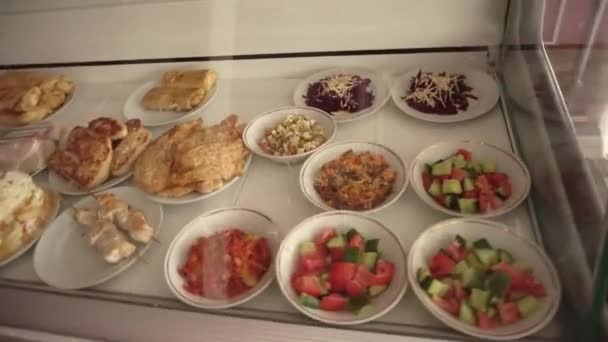 Еда в школьной столовой на витрине, салаты и мясные отбивные — стоковое видео
