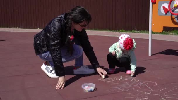 Kleines Mädchen spielt mit Mama auf dem Spielplatz, zeichnet mit bunten Buntstiften, Hintergrund, glücklich — Stockvideo