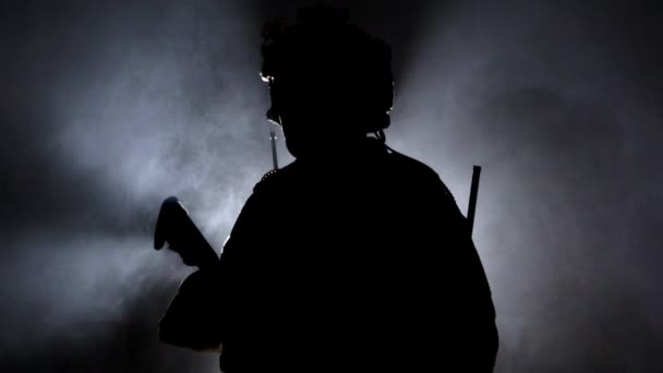 Wojskowy żołnierz w wojskowym sprzęcie z bronią palną na czarnym tle. Podświetlenie, operacje wojskowe — Wideo stockowe