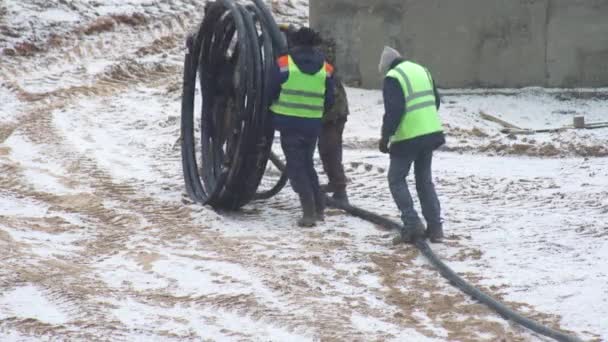 İşçiler inşaat alanında, arka planda, sanayide, ekipmanda bir kabloyu söküyorlar. — Stok video