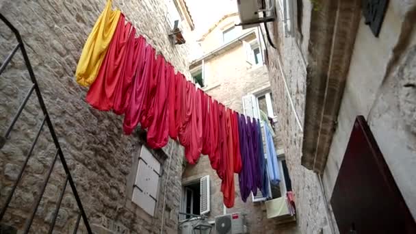Tecido multicolorido bonito pende na cidade velha na Grécia contra o fundo de paredes de pedra, câmera lenta, tradicional — Vídeo de Stock