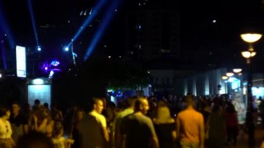 BUDVA, MONTENEGRO - 6 Temmuz 2019: Budva 'nın gece şehrinde yürürken, insanlar gece ışıkları, yavaş çekim, turizm ile aydınlanan caddelerde yürürler.
