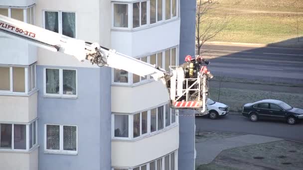 Samochód strażacki platformy powietrznej podnosi strażaków w koszu ochronnym, aby ugasić pożar w wielopiętrowym wieżowcu, strażak — Wideo stockowe