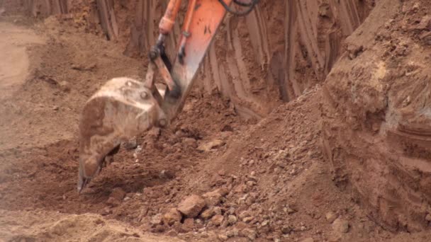 Un escavatore scava terreno argilloso in una fossa di fondazione per costruire una fondazione. Secchio di ferro escavatore con terra, sfondo, industria — Video Stock