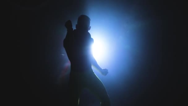 Young muscular and sexy man dancing in the shadow on the background of a spotlight — Stock Video