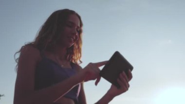 Gülümseyen kıvırcık saçlı, tablet bilgisayarlı kız online mağazaya sipariş veriyor ve ödeme yapıyor. Uzaktan Shoping. Haberleri izleyen bir kadın. İletişim. Vlogger. Düşük açılı çekim
