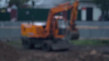 Yağmurda bir inşaat alanının arka planına kum yüklemek için kazıcı. Bulanık, kopyalama alanı, endüstri