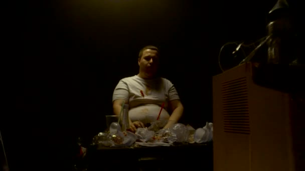 Grubas jedzący hamburgery i hot dogi z jedzeniem śmieci i oglądający telewizję, wolne mo, nadwaga — Wideo stockowe