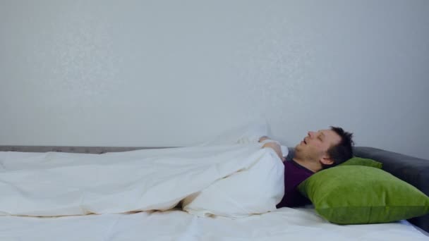 Un hombre salta de la cama mientras duerme cuando tiene una pesadilla. El concepto de mal sueño e insomnio, fobia — Vídeo de stock