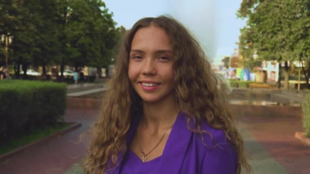 Portrait of curly long haired smiling girl without makeup. Natural beauty without products cosmetic care. Vogue female looks into a camera. Fashionable stylish woman stands still in slow motion — Stock Video