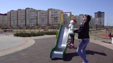 Küçük güzel beyaz kız annesiyle oyun parkında oynuyor. Güneşli bahar havası arka plan, açık hava