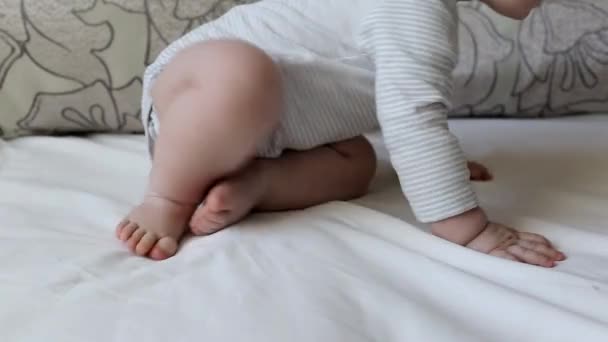 Маленький мальчик с толстыми ногами ползает на кровати, фон, в возрасте 7 месяцев — стоковое видео