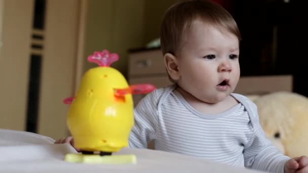 Menino caucasiano brinca com um brinquedo e bocejos, fundo — Vídeo de Stock