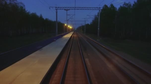 Akşamları son vagon vagonunun arka camından hareket halindeki raylara bakın. Tren bir yolcu istasyonunun önünden geçiyor ve şehir dışına çıkıyor. Elektrik çoklu birim — Stok video