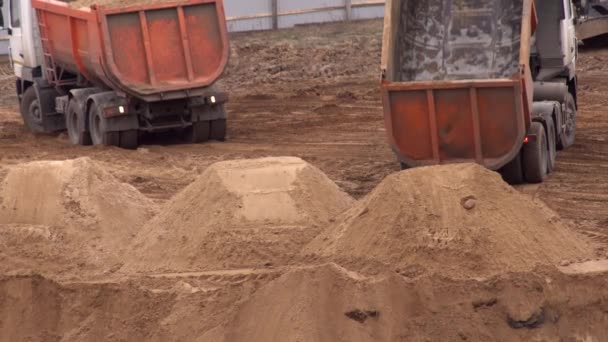 Een zware vrachtwagen giet zand uit een lichaam in een steengroeve. Bouwmateriaal van zand. Het lossen van de bodem van een vrachtwagen lichaam, achtergrond, industrie — Stockvideo