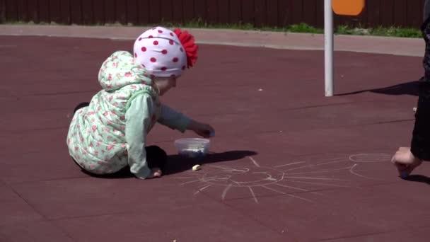 Liten flicka leker med mamma på lekplatsen, ritar med färgglada kritor, bakgrund, glad — Stockvideo