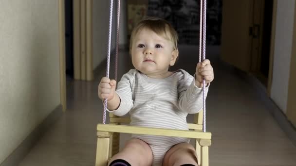 Pequeno caucasiano menino montando em um balanço em casa, felicidade — Vídeo de Stock