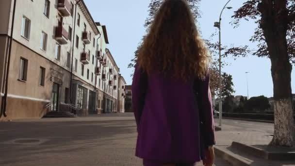 Idea da donna d'affari. Ragazza dai capelli ricci in giacca e cravatta cammina lungo la strada della città, vista posteriore sul retro. Vogue femmina va da sola. Donna alla moda elegante si muove al rallentatore. Trendy signora è all'aperto — Video Stock