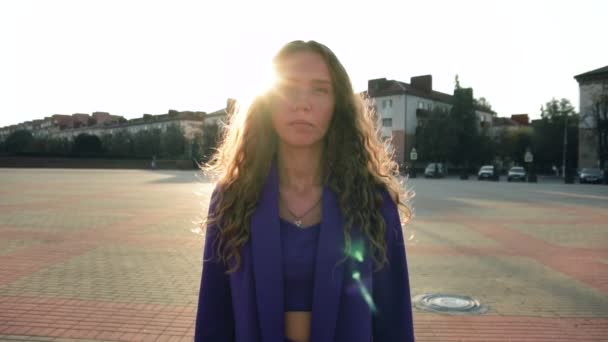 Portrait of cute image caucasian curly long haired girl in a suit without makeup at sunset under sun rays. Vogue female looks into a camera. Fashionable stylish woman. Trendy fancy business lady — Stock Video