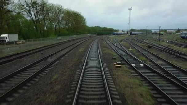 Zicht op rijdende rails vanuit de achterruit van de laatste wagon overdag. Spoorwegpassagierstrein die de stad verlaat. Reizen en toerisme. — Stockvideo