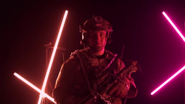 Серьезный кавказский солдат в военной форме с оружием стоит и смотрит в камеру. Металлические цепи и солдаты, концепция плена и заложника, замедленная съемка — стоковое видео